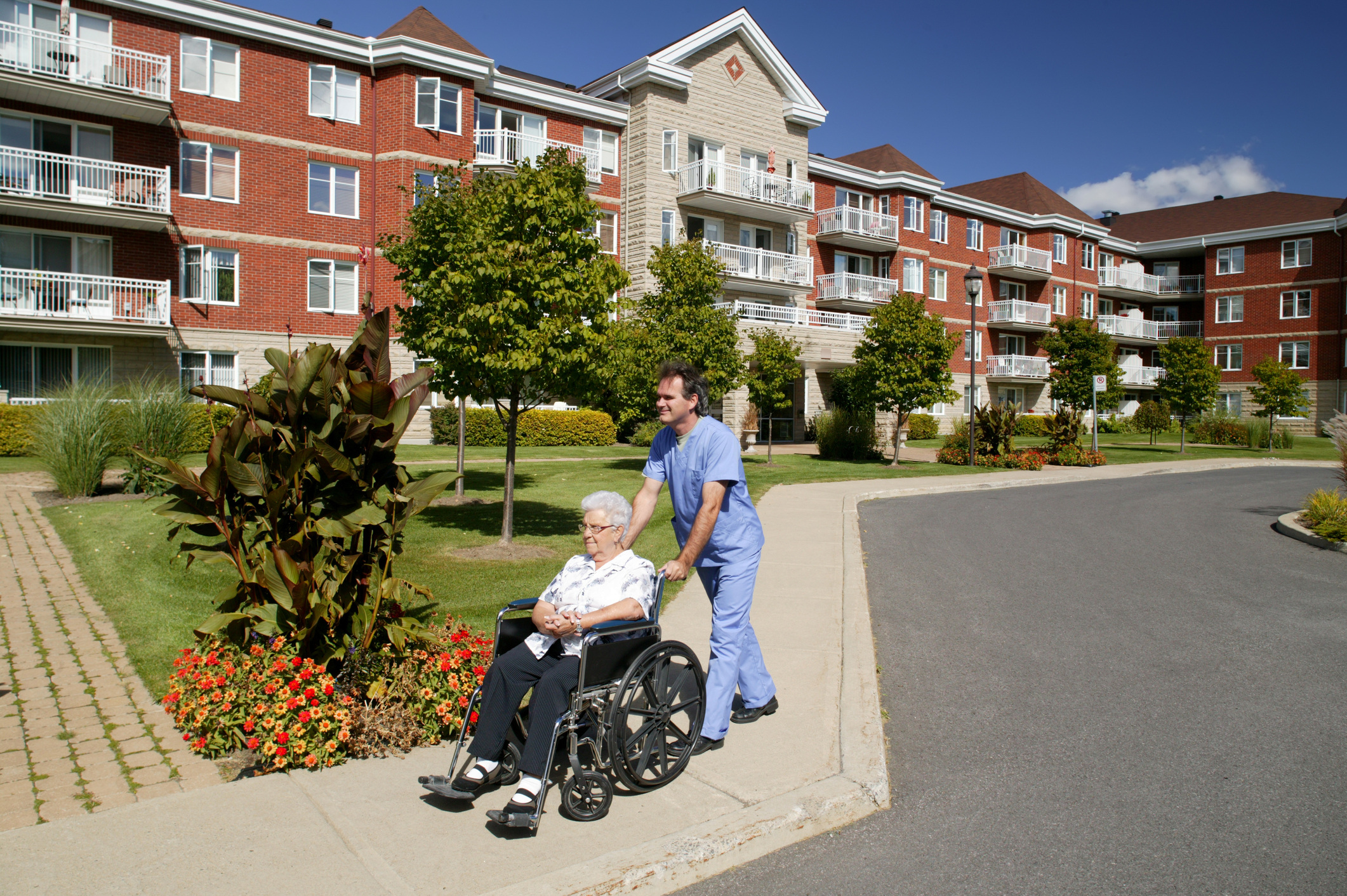 Nurse pushing resident outside housing complex