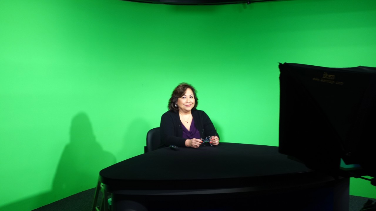 Woman sitting in front of green screen